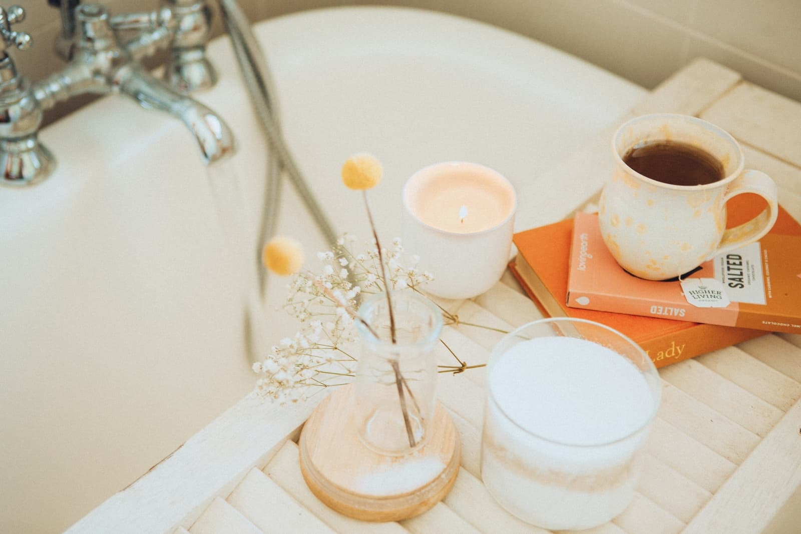 A steaming cup of coffee resting on the edge of a full bath